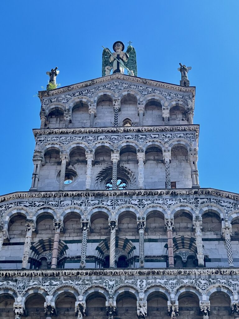De bovenkant van de façade van de San Michele in Foro met bovenop de aartsengel Michael